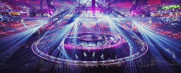Escenario de arena iluminado con haces de luz blanca y lavado de luz púrpura