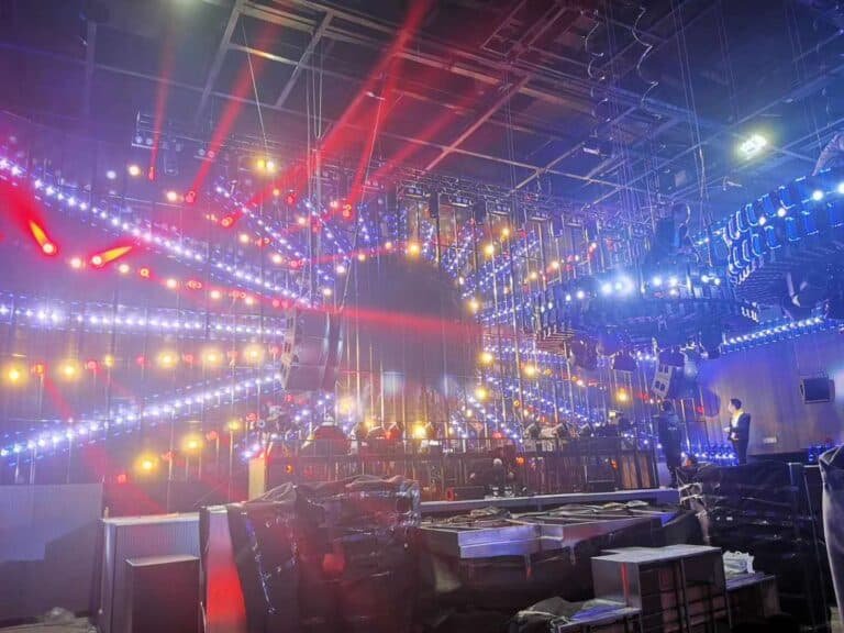 Interior de club con iluminación de escenario roja, azul y blanca sobre el área de asientos